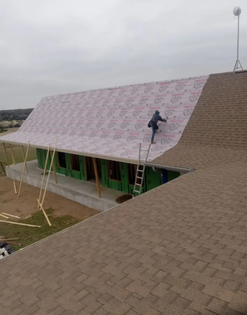 Worker preparing underlayment for a metal roof installation in Burlington